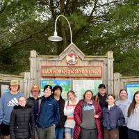 Careerline Tech Students posing for a picture in front of an Ottawa Parks intrance map outside, standing in the snow with evergreens behind them